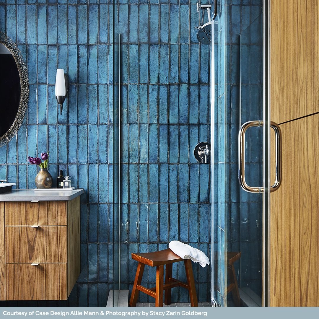 Deep blue horizontally laid subway tiles in a shower environment. The tiles are textured in colours and aren't a standard subway tile by any means. 