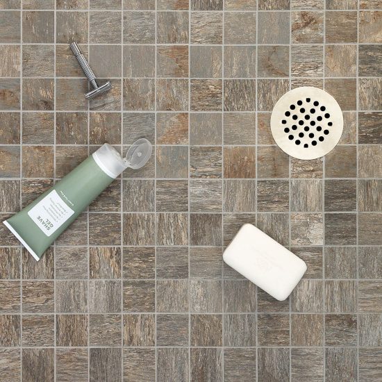 Small square wood look tiles used on shower floor around circular drain. 