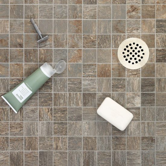 Small square wood look tiles used on shower floor around circular drain.