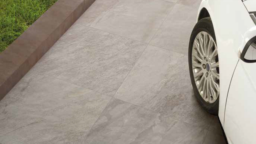 Pavers are shown on a driveway with no gaps between them. A car wheel and wheel arch is seen in the corner of a photo indicating they are good to drive on. 