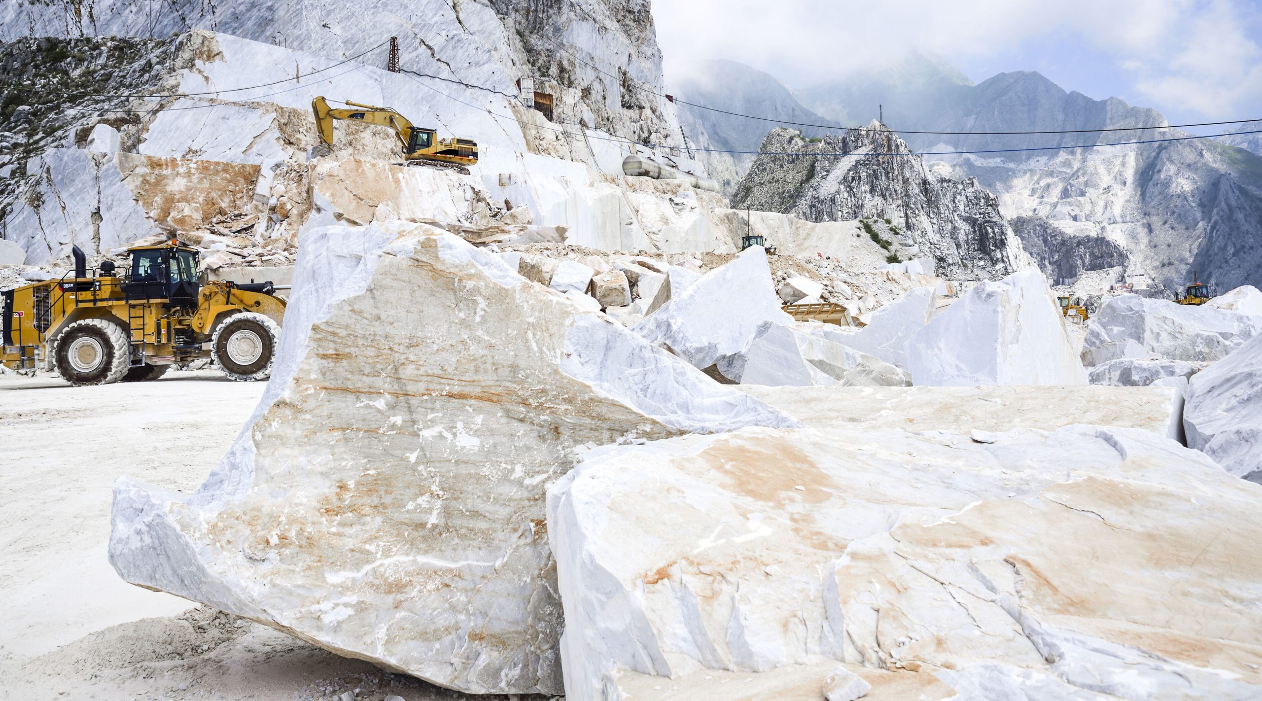A quarry where they mine for Terrazzo rocks - a large truck and a white rock are pictured in a mountain area 